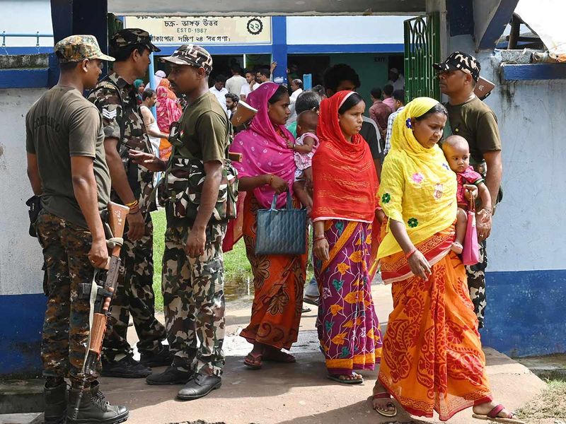 Paramilitary personnel stand guard at the entrance of a polling station during West Bengal's 'Panchayat' or local elections, on the outskirts of Kolkata on July 8, 2023.