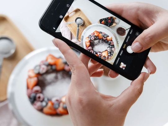 Food photography: Woman hand taking photo of cake