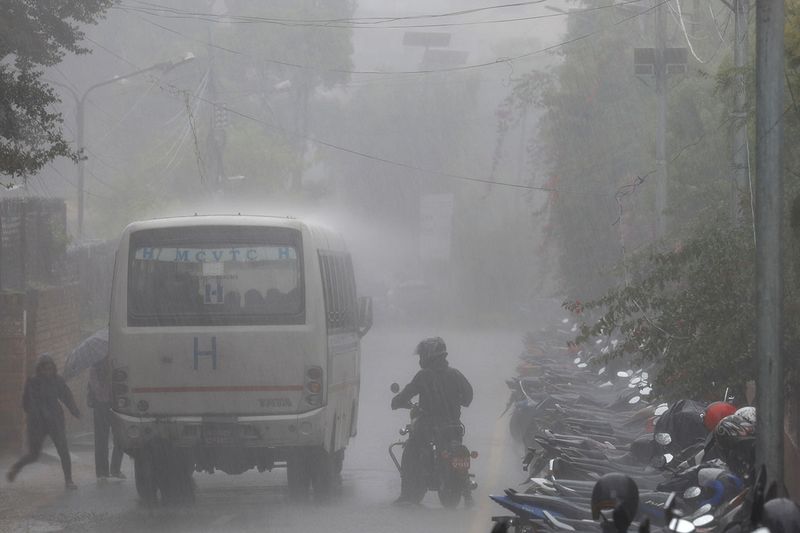 People rush towards a bus during heavy rain in Kathmandu, Nepal July 11, 2023. 