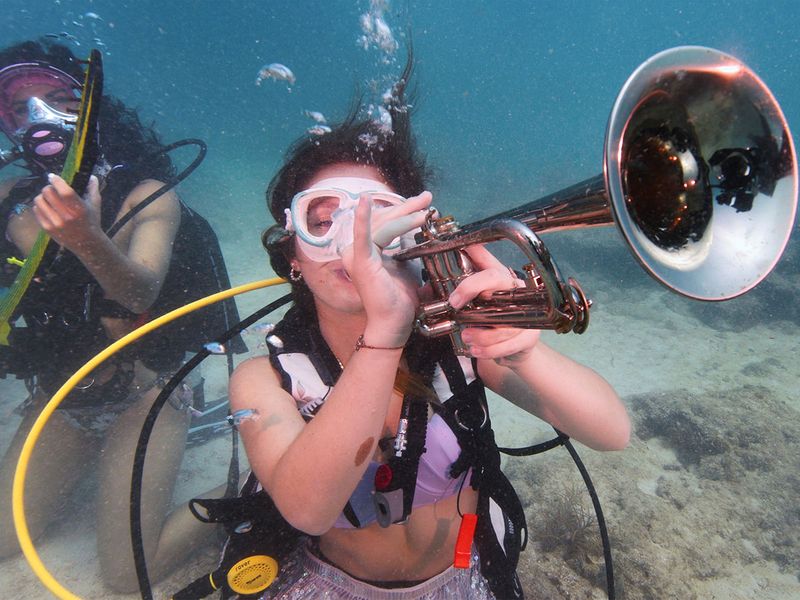 Kelly Angel, left, and Kara Norman, right, pretend to play underwater musical instruments