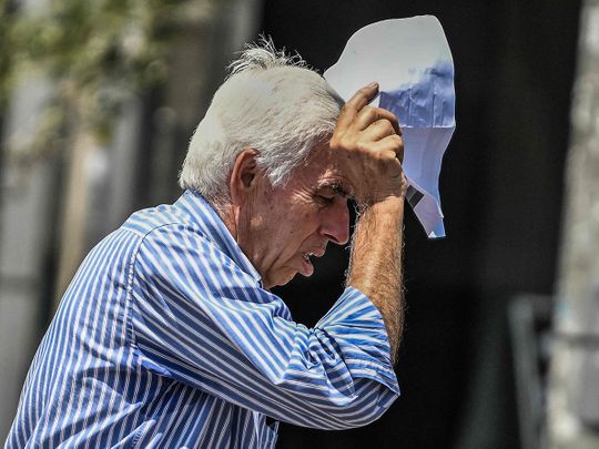 An elderly man holds a piece of paper over his head to protect himself from the sun in Athens, on July 13, 2023. Greece's national weather service EMY on July 10, 2023, said a six-day heatwave would grip Greece starting July 12.
