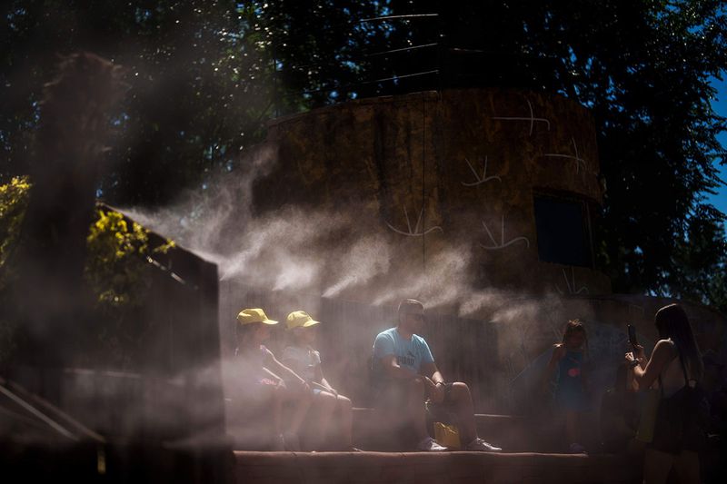 People cool off with water mist at at the Madrid Zoo, Spain, Thursday, July 13, 2023. Much of Spain was enjoying a brief respite Thursday from the suffocating temperatures of the second heatwave of the summer, which ended Wednesday. 