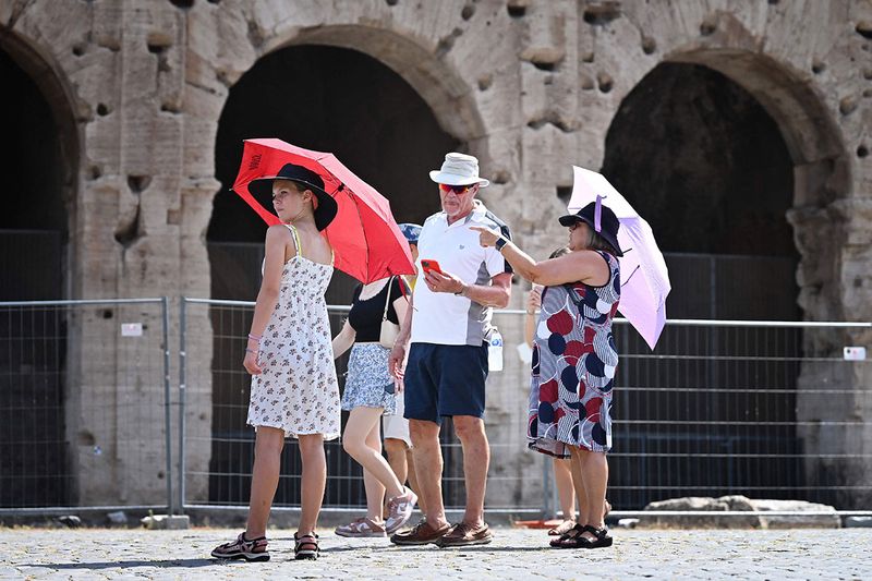 Tourists shelter from the sun with umbrellas near the Colosseum in Rome, on July 14, 2023, as Italy is hit by a heatwave
