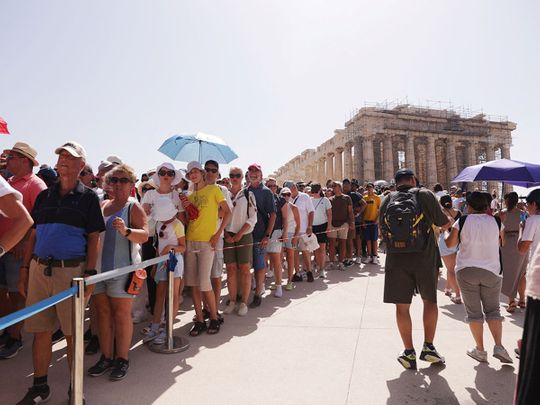 Visitors walk near the Parthenon temple atop the Acropolis hill, during a heatwave in Athens, Greece, July 14, 2023.