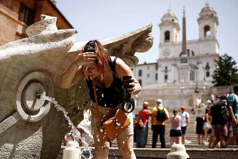 A woman cools off at Fontana della Barcaccia at the Spanish Steps during a heat wave across Italy as temperatures are expected to rise further in the coming days, in Rome, Italy July 17, 2023.