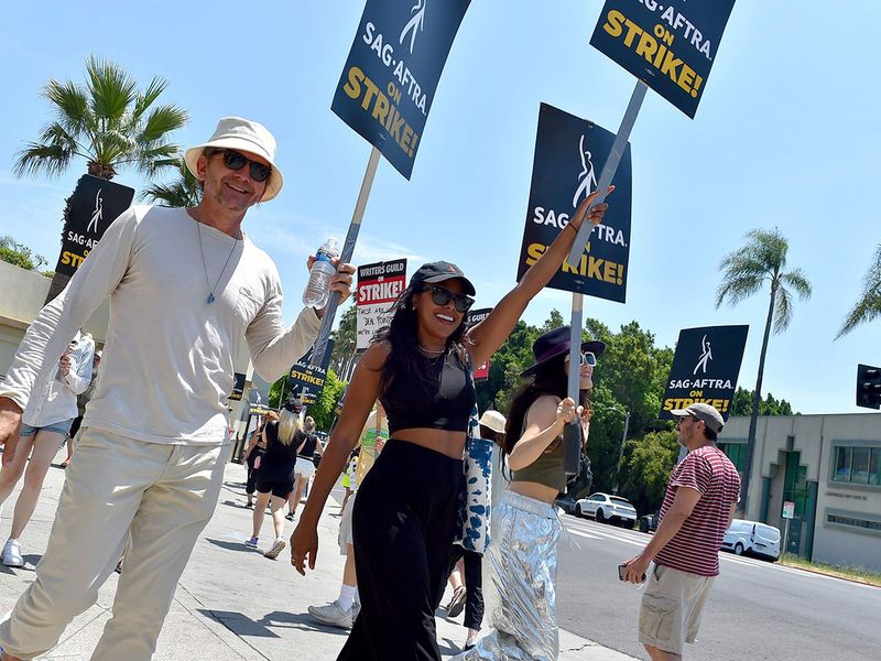 Actors Sebastian Roche, from left, Meagan Holder and Alicia Hannah-Kim carry signs on a picket line outside Paramount studios in Los Angeles on Monday, July 17, 2023. The actors strike comes more than two months after screenwriters began striking in their bid to get better pay and working conditions and have clear guidelines around the use of AI in film and television productions. 