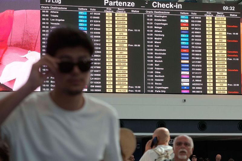 Passengers look at a monitor with the departure times of flights during a nationwide strike of airports ground staff, and check-in services at Rome's Fiumicino International airport in Fumicino, Italy, Saturday, July 15, 2023. 