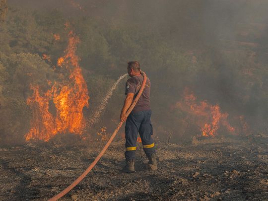 Firefighter Nektarios Kefalas tries to extinguish a wildfire burning near the village of Asklipieio, on the island of Rhodes, Greece, July 24, 2023. 