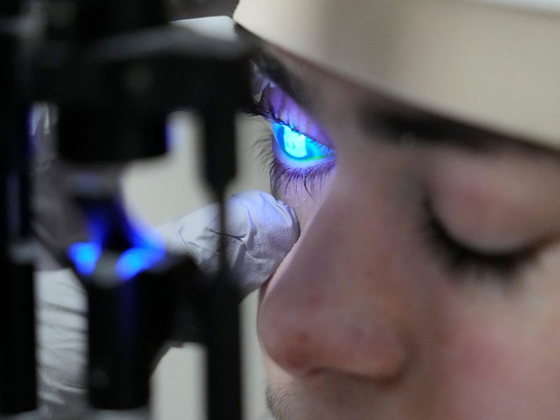 Dr. Alfonso Sabater, checks Antonio Vento Carvajal's eye under a blue light after applying a stain to check to see if more ulcers had developed, before a gene therapy treatment, at University of Miami Health System's Bascom Palmer Eye Institute in Miami. 