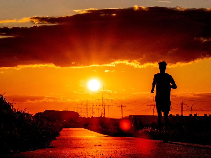 A man runs along a small road in the outskirts of Frankfurt, Germany, as the sun rises. 