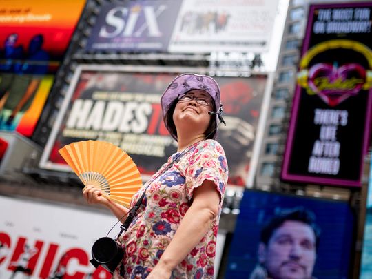 A tour guide fans herself while working in Times Square as temperatures rise, in New York