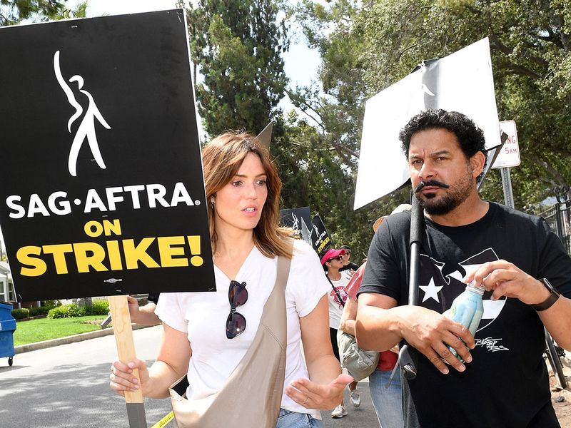 US actress Mandy Moore (L) and US actor John Huertas join members of the Writers Guild of America and the Screen Actors Guild as they walk a picket line outside of Walt Disney Studios in Burbank, California, on August 1, 2023. Tens of thousands of Hollywood actors went on strike at midnight July 14, 2023, effectively bringing the giant movie and television business to a halt as they join writers in the first industry-wide walkout for 63 years. 