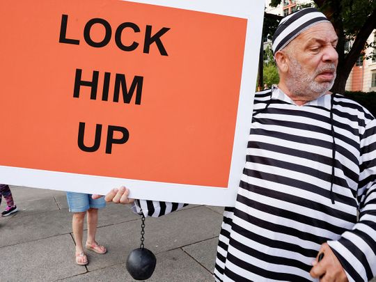 A man holds a sign in front of the E. Barrett Prettyman Federal Courthouse