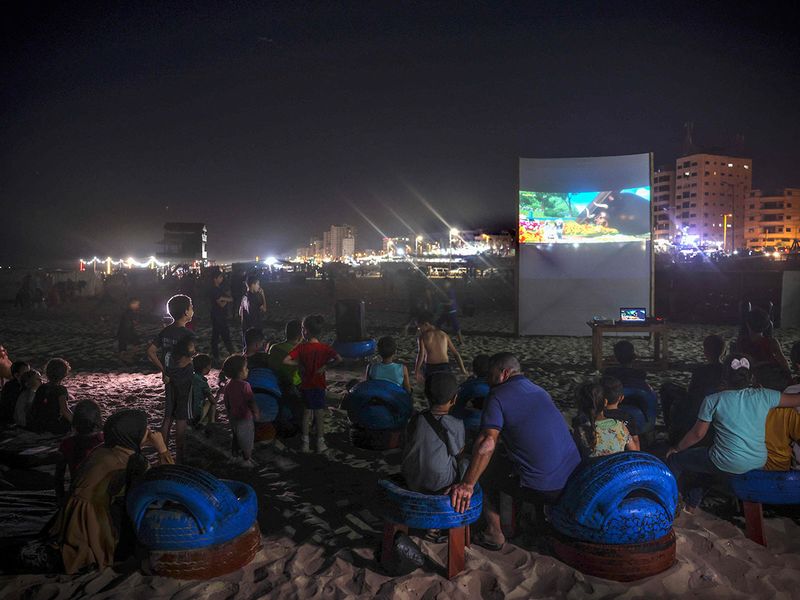 Palestinian children watch a movie at a pop-up open-air cinema at the beach in Gaza city on July 28, 2023, as there are no movie theatres in the blockaded Gaza Strip. 