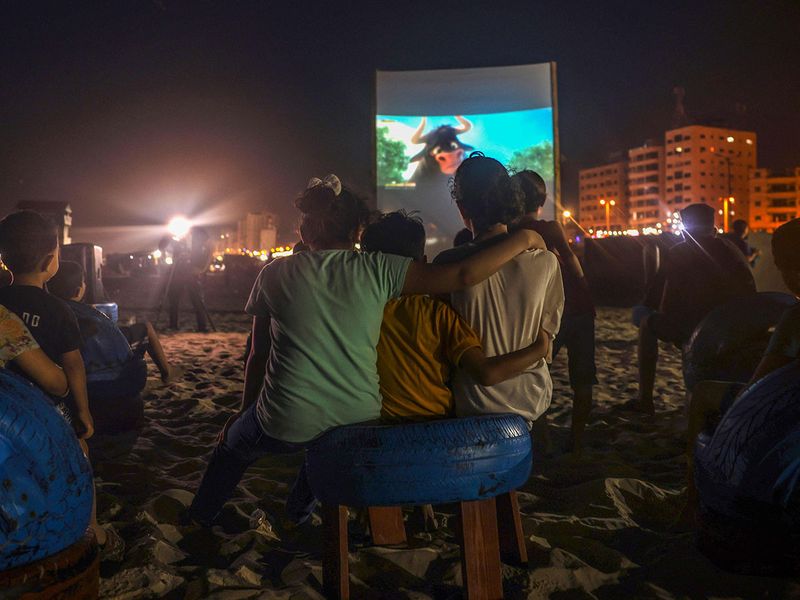 Palestinian children watch a movie at a pop-up open-air cinema at the beach in Gaza city on July 28, 2023, as there are no movie theatres in the blockaded Gaza Strip. 