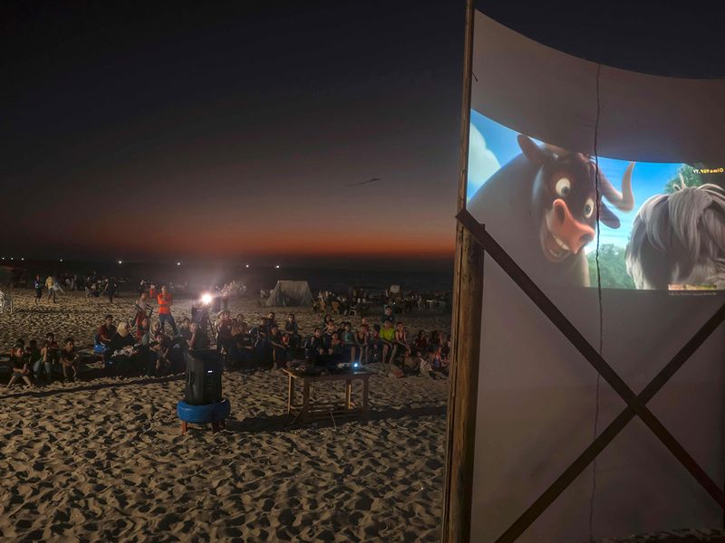 Palestinian children watch a movie at a pop-up open-air cinema at the beach in Gaza city on July 28, 2023, as there are no movie theatres in the blockaded Gaza Strip.