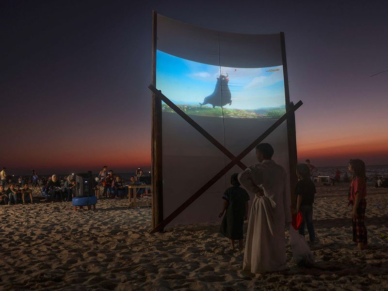 Palestinian children watch a movie at a pop-up open-air cinema at the beach in Gaza city on July 28, 2023, as there are no movie theatres in the blockaded Gaza Strip.