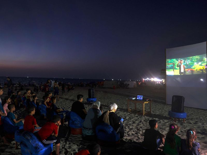 Palestinian children watch a movie at a pop-up open-air cinema at the beach in Gaza city on July 28, 2023, as there are no movie theatres in the blockaded Gaza Strip.