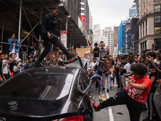 People jump on a car during riots sparked by Twitch streamer Kai Cenat, who announced a 