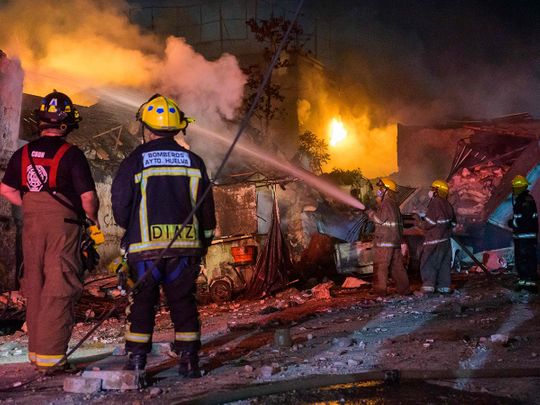 Firefighters work to extinguish a fire after an explosion in a commercial establishment in San Cristobal, Dominican Republic.  