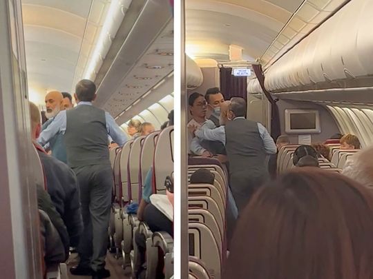 In this image taken from a video, a passenger standing in the aisle, second right, argues with crew members during a flight from Australia to Malaysia, Monday, Aug. 14, 2023