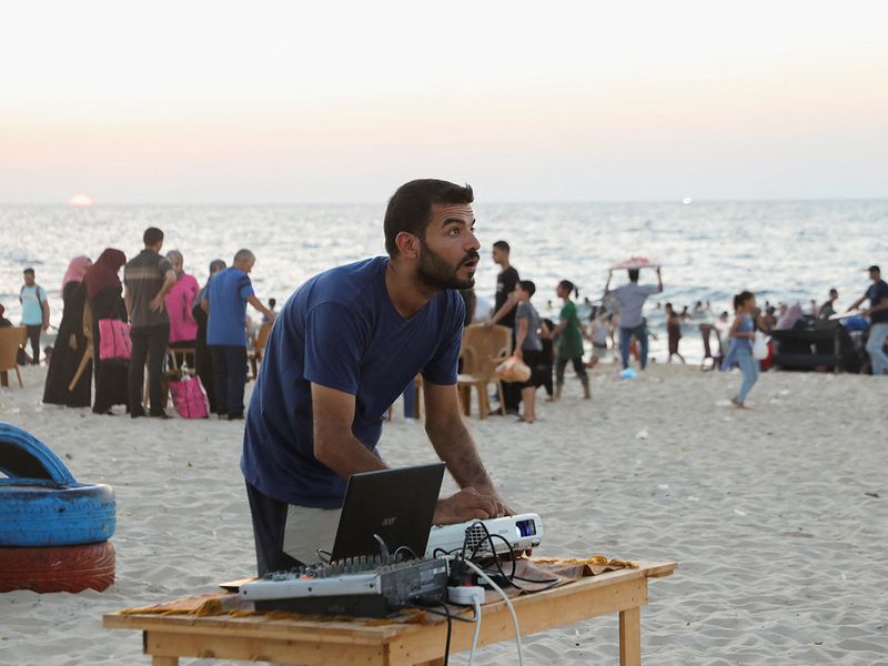 A man prepares a large projector screen at a beachfront cafe, for a rare cinema event, in Gaza City. 