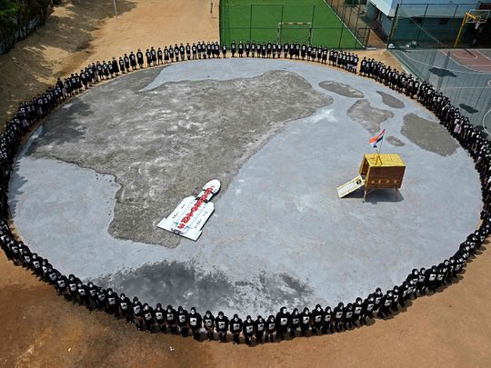 Students with painted faces form a circle around a replica of the Chandrayaan-3 spacecraft in Chennai