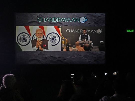 People watch as India's Prime Minister Narendra Modi (L) congratulates the Indian Space Research Organisation (ISRO) for the successful lunar landing of Chandrayaan-3 spacecraft on the south pole of the Moon during a live stream of the event at a museum in Kolkata on August 23, 2023.