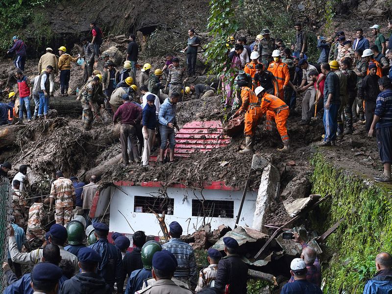 Rescuers remove mud and debris as they search for people feared trapped after a landslide near a temple on the outskirts of Shimla, Himachal Pradesh, on August 14, 2023. 