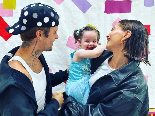 Pop star Justin Bieber and wife Hailey pose with a child.