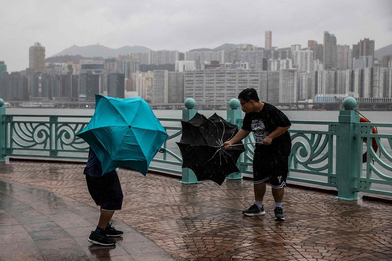  People struggle with their umbrellas in high winds brought by Super Typhoon Saola next to Victoria harbour in Hong Kong on September 1, 2023. Super Typhoon Saola threatened southern China on September 1 with some of the strongest winds the region has endured, forcing the megacities of Hong Kong and Shenzhen to effectively shut down. 