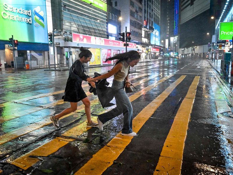 People run for cover from the rain and high winds brought by Super Typhoon Saola in Causeway Bay in Hong Kong.