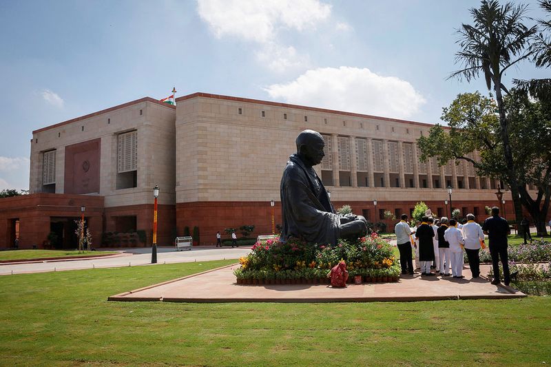 A statue of Mahatma Gandhi is pictured next to India's new parliament building a day before the inauguration of the building in New Delhi, India, September 18, 2023. REUTERS/Adnan Abidi