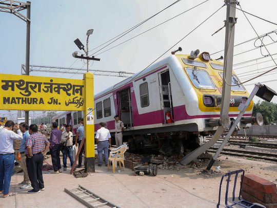 Police personnel and people gather near an electric multiple unit (EMU) train