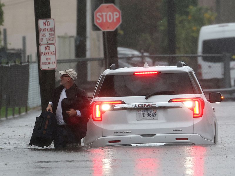 A man carries his belongings as he abandons his vehicle which stalled in floodwaters during a heavy rain storm in the New York City suburb of Mamaroneck in Westchester County, New York, U.S., September 29, 2023. 