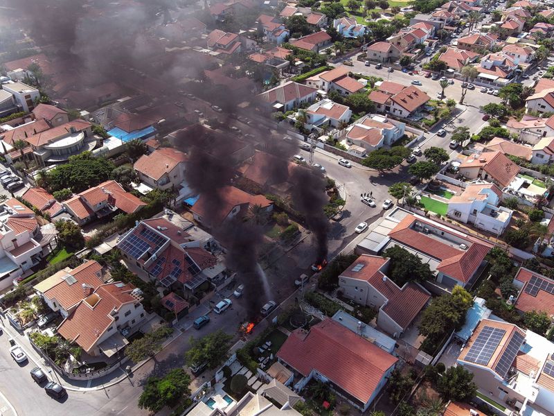 An aerial view shows vehicles on fire as rockets are launched from the Gaza Strip