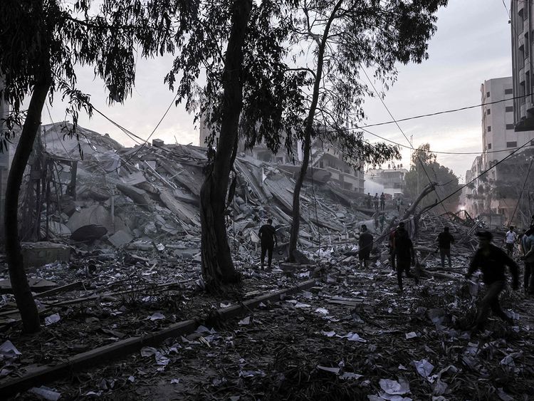 People walk atop the rubble of a tower destroyed in an Israeli air stike in Gaza City on October 7, 2023.  