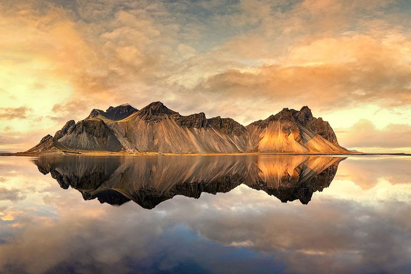 A panorama of sunset at Vestrahorn, Stokksnes peninsula. Golden hour shot with mirror reflection at dusk. South-east Iceland in autimn. 