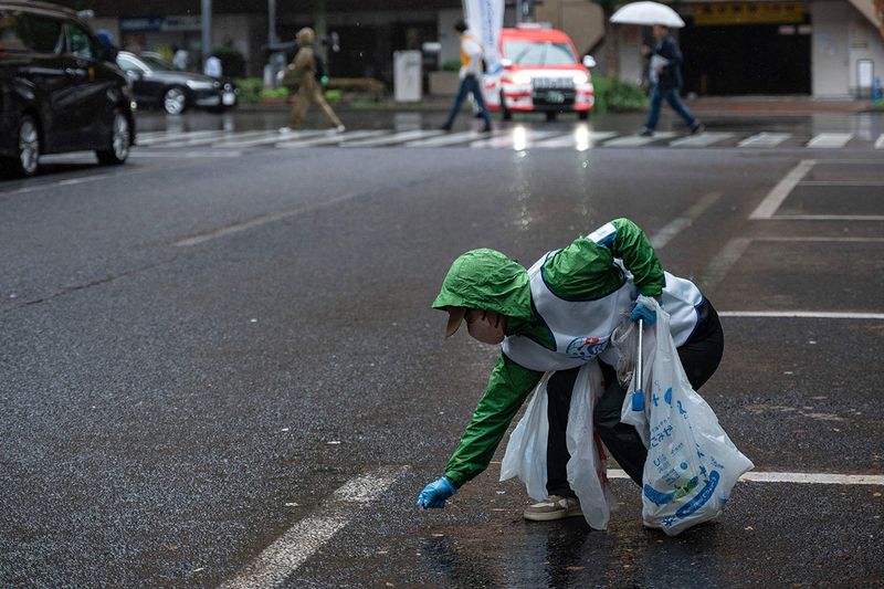 A participant picks up trash from the street as she takes part in the Japan stage of the 
