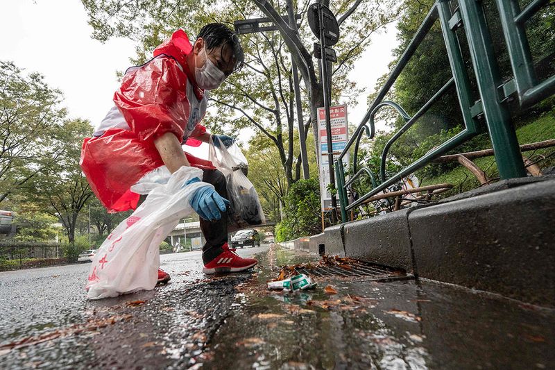 A participant picks up trash from the street during the Japan stage of the 