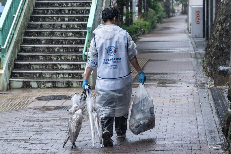 A participant walks back to the collection centre with a bag of trash and discarded umbrellas found while taking part in the Japan stage of the 