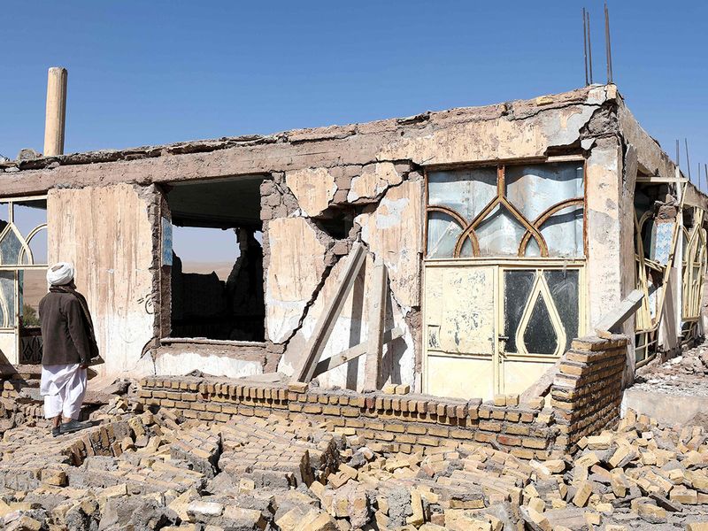 An Afghan man stands near a damaged house after the earthquakes in Sarbuland village, Zendeh Jan district of Herat province on October 8, 2023.