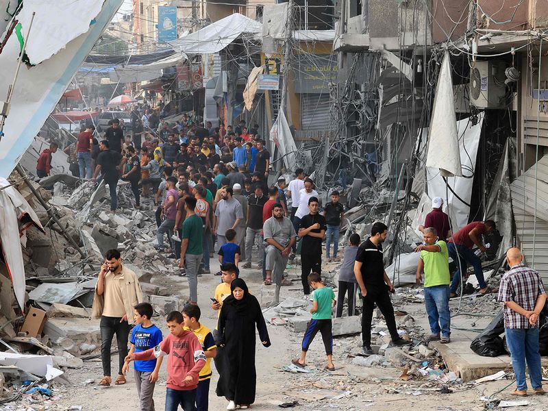 Palestinians walk amid the rubble of destroyed and damaged building 