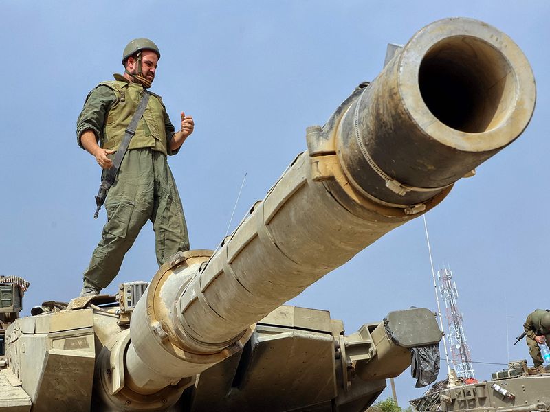 A soldier stands on the turret of a tank as Israeli forces take positions 