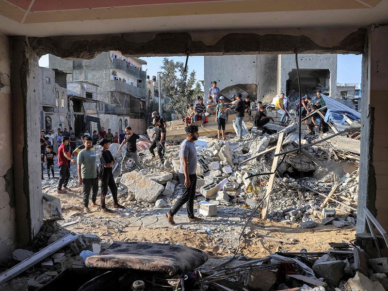People gather by the rubble of a building in the aftermath of an Israeli air strike in Rafah in the southern Gaza Strip on October 13, 2023. 