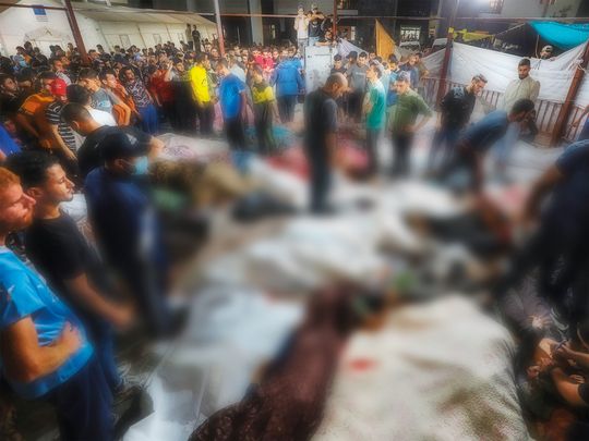 People gather around bodies of people killed in Israeli airstrikes on the Al Ahli Baptist Hospital