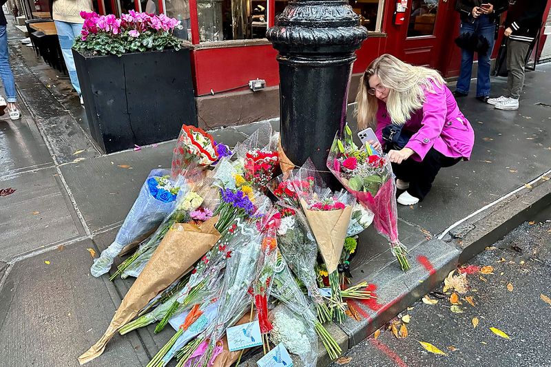 A person takes pictures of a makeshift memorial for Matthew Perry outside the building known as the 