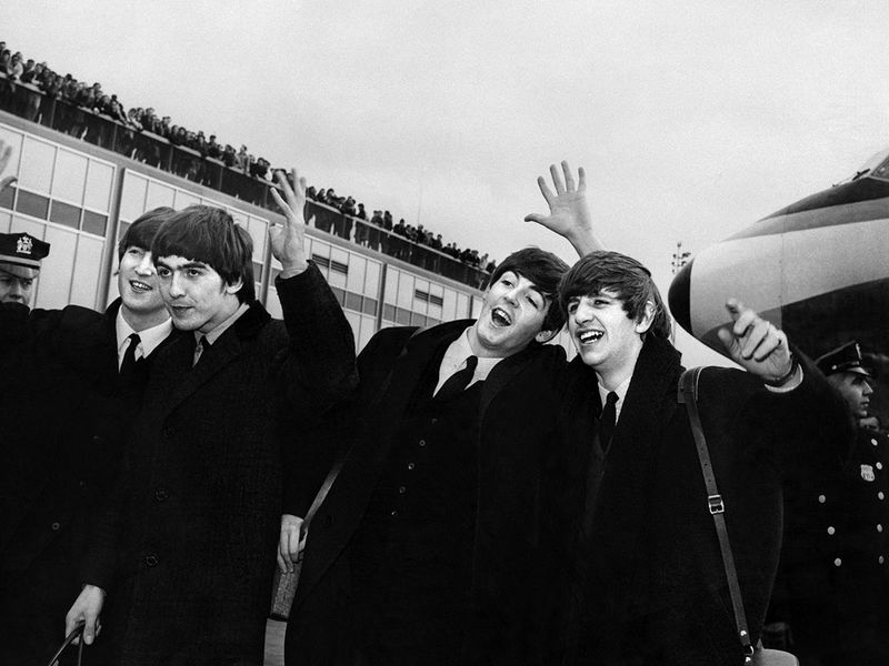 English band the Beatles with, from left to right, John Lennon, Ringo Starr, Paul McCartney and George Harrison, arrive at John F. Kennedy Airport in New York, United States, where they're greeted by a large crowd on February 7, 1964. 