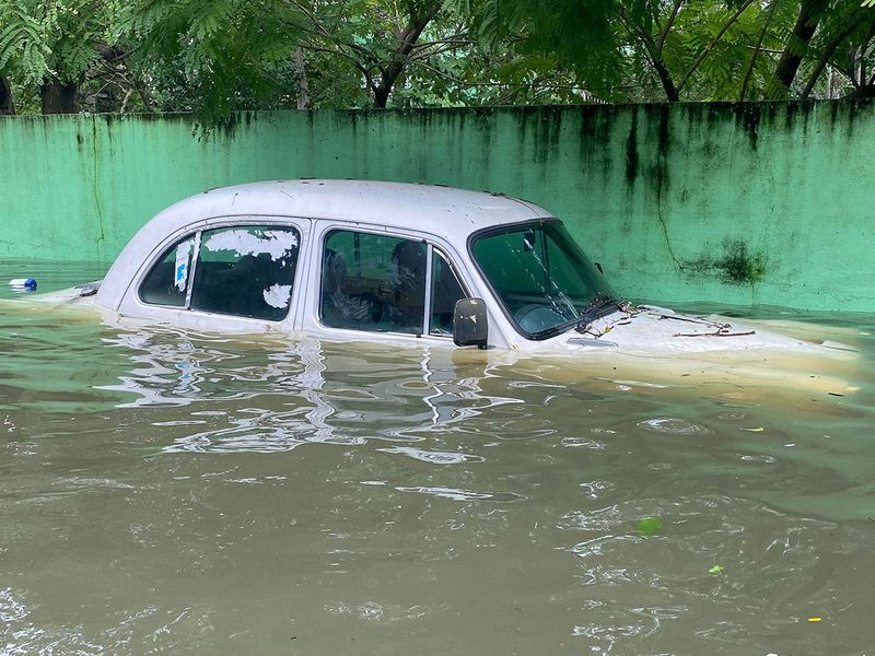 A car is seen partially submerged in a flooded street in Chennai on December 5, 2023, following intense rains after Cyclone Michaung made a landfall. Chest-high water surged down the streets of India's southern city Chennai on December 5, with eight people killed in intense floods as Cyclone Michaung made landfall on the southeast coast. (Photo by R. Satish BABU / AFP)