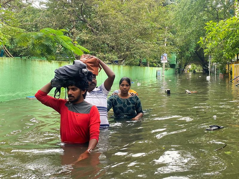 People wade along a flooded street in Chennai on December 5, 2023, following intense rains after Cyclone Michaung made a landfall. Chest-high water surged down the streets of India's southern city Chennai on December 5, with eight people killed in intense floods as Cyclone Michaung made landfall on the southeast coast. 